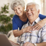 Happy grandparents using their digital laptop